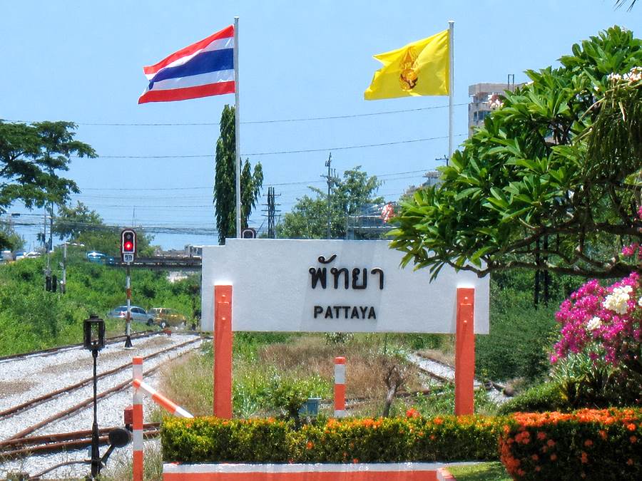 Bahnhofsschild Pattaya mit Bahngleisen und thailändischer Flagge