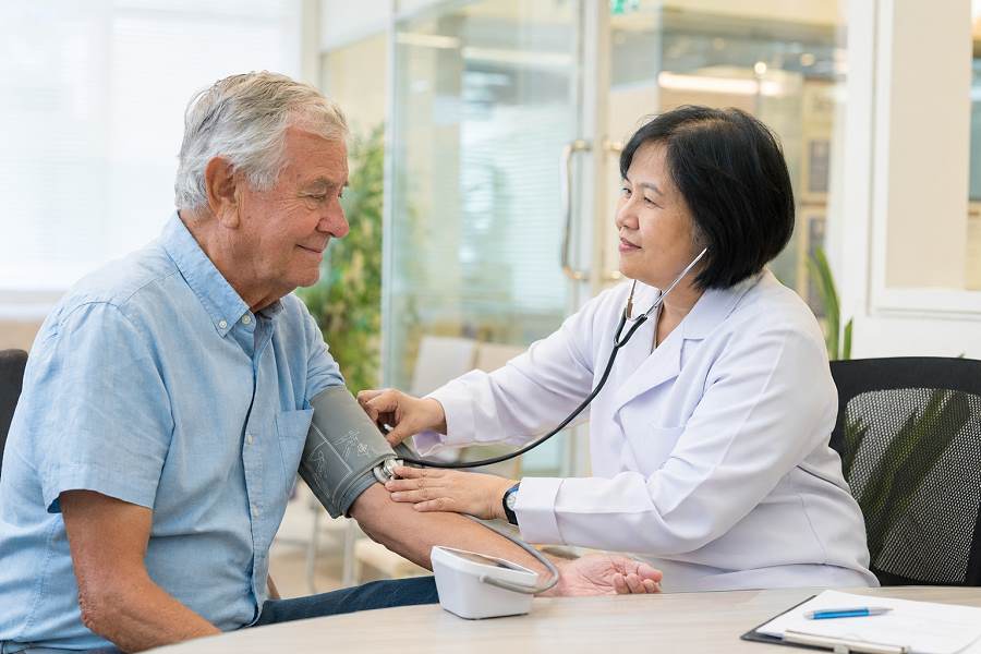 Thailändische Ärztin untersucht einen deutschen Rentner in einer Klinik