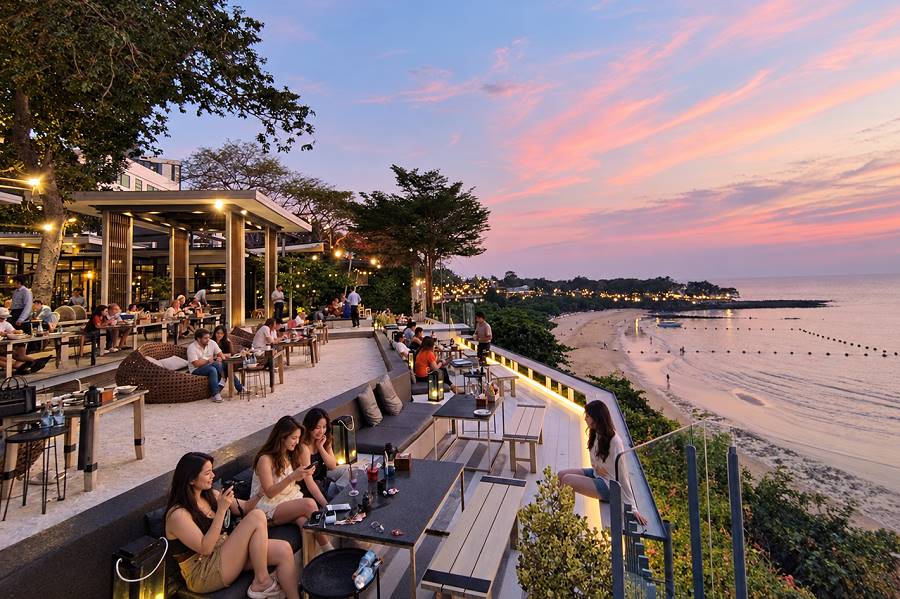 Restaurantterrasse mit Gästen und Blick auf den Strand bei Sonnenuntergang in Pattaya