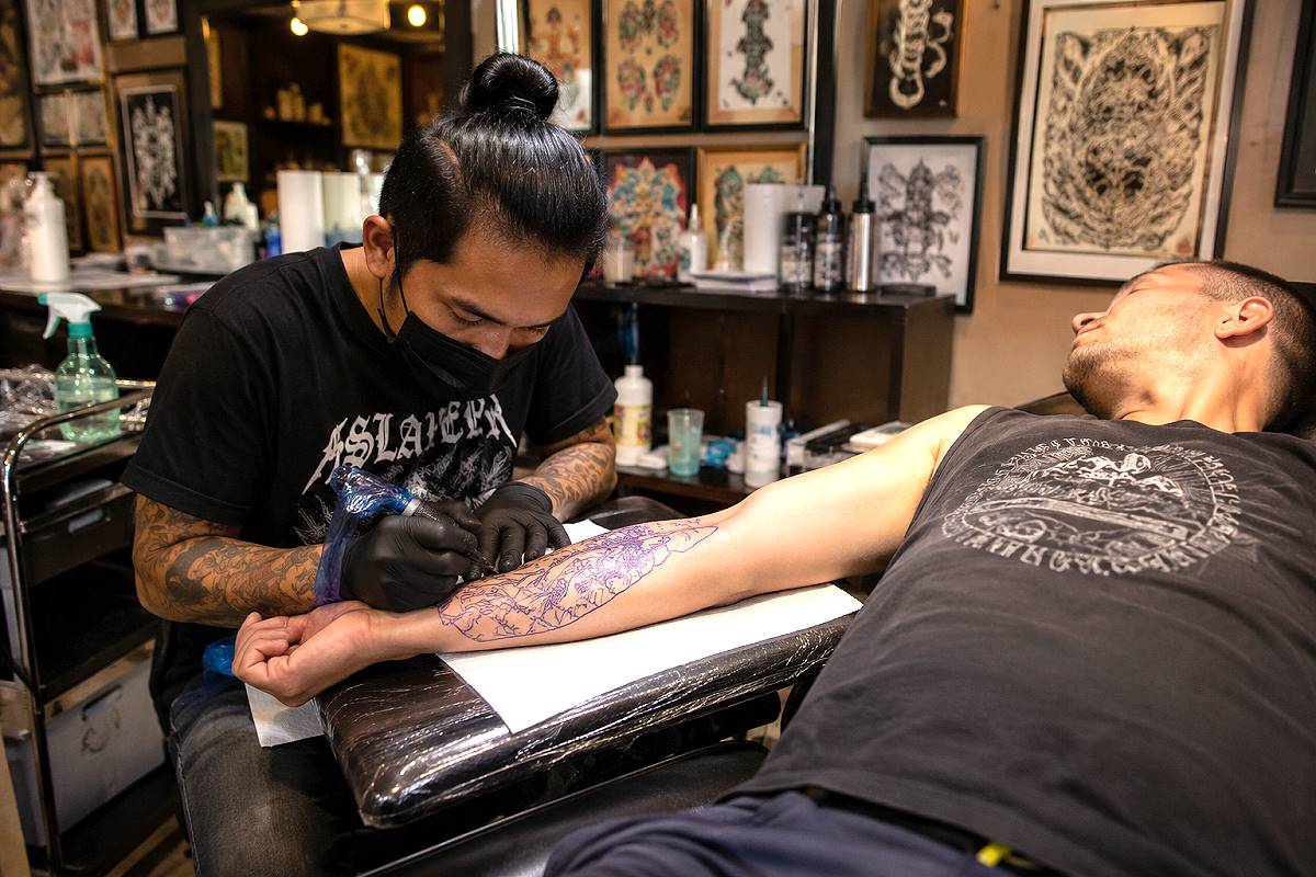 Tätowierer bei der Arbeit in einem Tattoo-Studio in Thailand