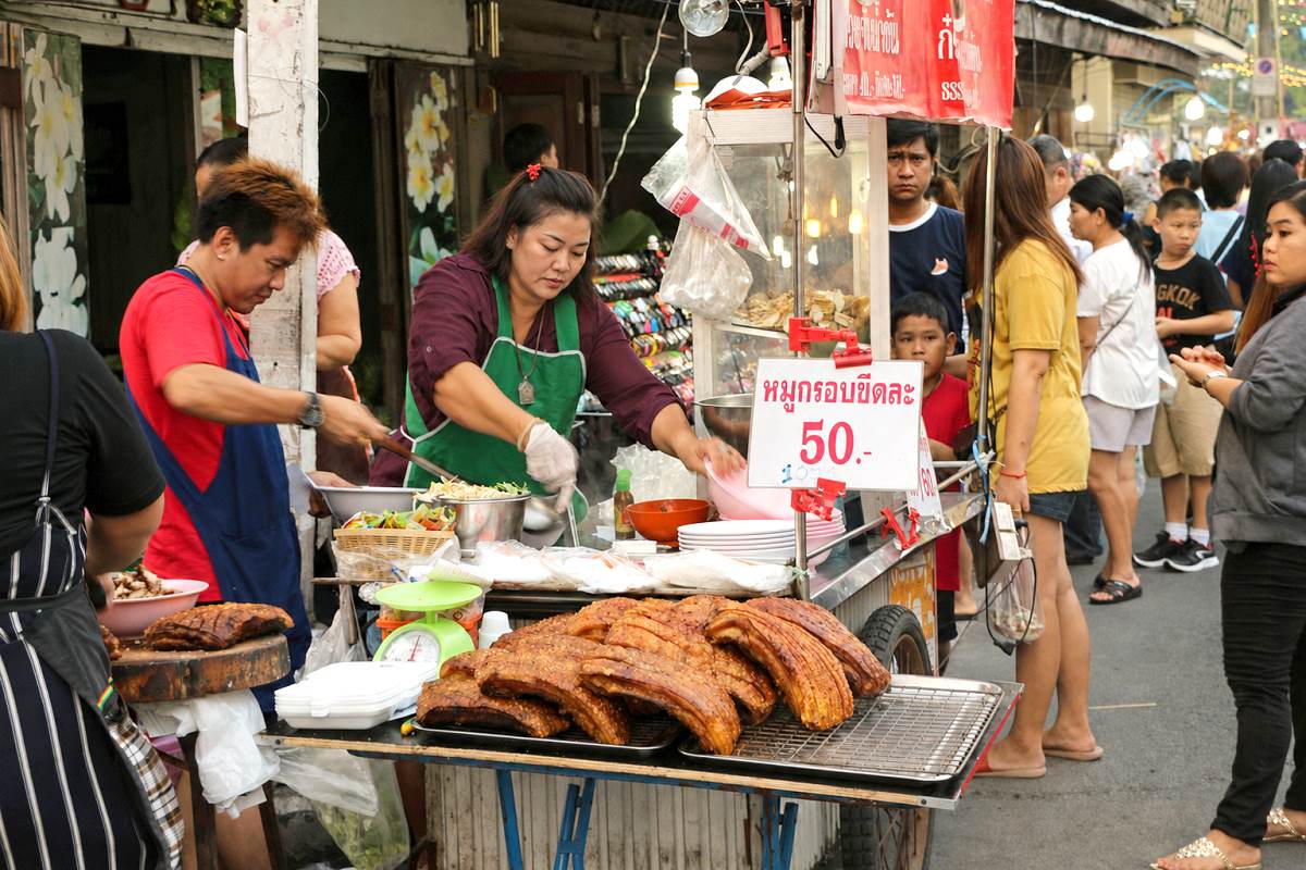 Thailändische Verkäuferinnen bereiten Thai Food an einem belebten Straßenstand zu