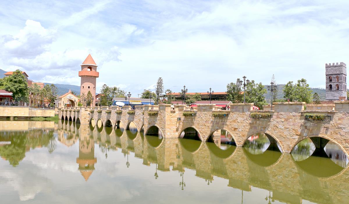 Bogenbrücke und Turm spiegeln sich im Wasser des Verona at Tub Lan