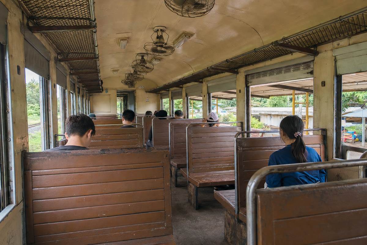 Dritte Klasse in einem thailändischen Zug mit Holzbänken und Ventilatoren